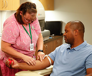 Health care provider drawing blood from man's arm.